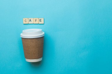 Kağıt kahve fincanı ve üzerinde mavi arka planda bir tabela olan bir kapak.