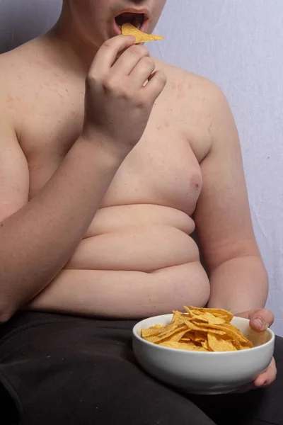 一个体重超标的高加索少年在吃一碗薯片 — 图库照片