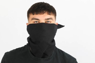 Beyaz arka planda siyah bir maske takan genç bir çocuk.