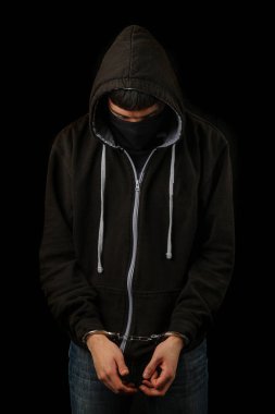 Elleri kelepçeli, maskeli ve kapüşonlu bir çocuk tutuklandı.