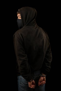 Elleri kelepçeli, maskeli ve kapüşonlu bir çocuk tutuklandı.