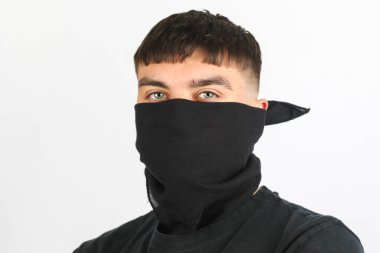 Beyaz arka planda siyah bir maske takan genç bir çocuk.