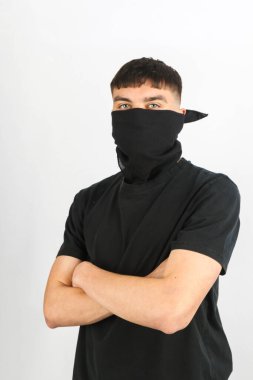 Beyaz arka planda siyah bir maske takan genç bir çocuk.