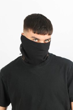 Beyaz arka planda siyah bir maske takan genç bir çocuk.