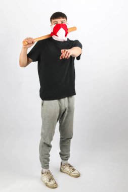 Beyzbol sopalı genç bir çocuk beyaz arka planda İngiltere Bayrağı maskesi takıyor.