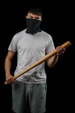 Beyzbol sopalı genç bir çocuk siyah arka planda maske takıyor.