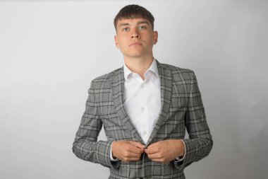 Takım elbiseli genç bir girişimci ve ceketini düzelten bir kravat takmadan açık yaka gömlek giyiyor.