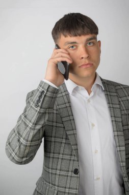 Takım elbiseli ve kravatsız bir gömlek giyen genç girişimci telefon kullanıyor.