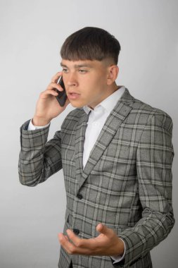 Genç girişimci takım elbise giyip, kravat takmadan bir telefon görüşmesini tartışıyor.