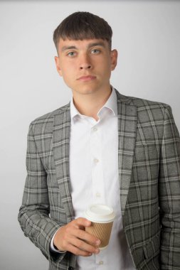 Takım elbiseli genç bir girişimci ve kravatsız bir boyun tişörtü giyiyor. Elinde kahve fincanı var.