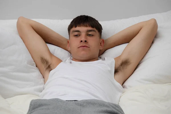 Young single male adult laying on top of his bed