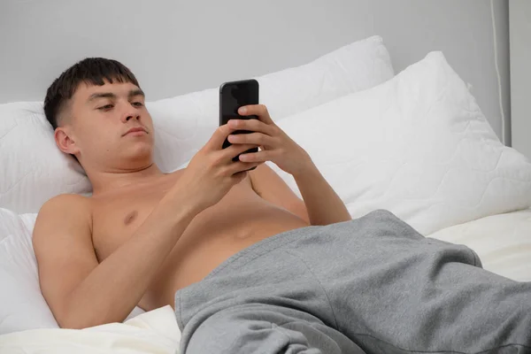 Jovem Adulto Solteiro Deitado Sem Camisa Cama Usando Seu Telefone — Fotografia de Stock