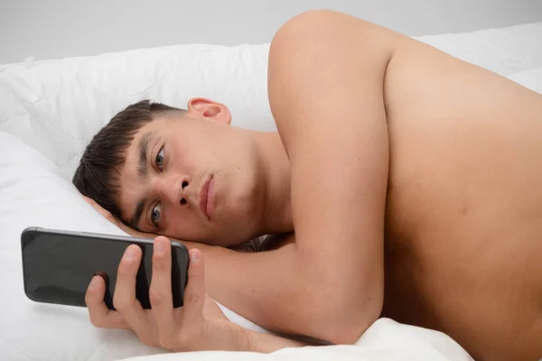 Jovem Adulto Solteiro Deitado Sem Camisa Cama Usando Seu Telefone — Fotografia de Stock