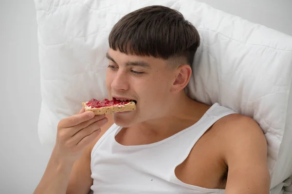Young single adult man having breakfast in bed