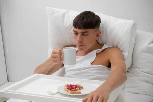 Young single adult man having breakfast in bed