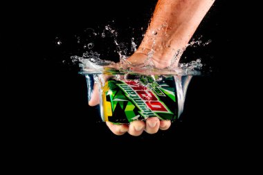 Londra, Birleşik Krallık, 24 Temmuz 2023: Bir şişe Mountain Dew, siyah arka planda suya çarpıyor.