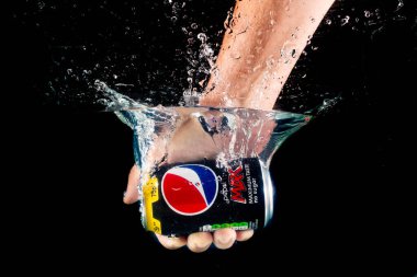 Londra, Birleşik Krallık, 24 Temmuz 2023: Bir kutu Pepsi Max, siyah arka planda suya düşen bir elle tutuldu
