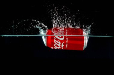 Londra, Birleşik Krallık, 24 Temmuz 2023: Bir kutu Coca-Cola siyah arka planda suya sıçrıyor