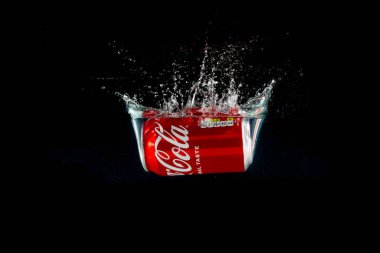 Londra, Birleşik Krallık, 24 Temmuz 2023: Bir kutu Coca-Cola siyah arka planda suya sıçrıyor