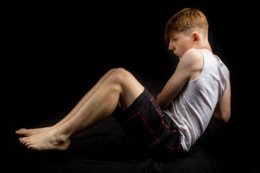 14 yaşında kolsuz yelek giyen beyaz bir çocuğun portresi. Siyah arka plan çocuğuna karşı Rus kıvrımları yapıyor.