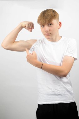 14 yaşında beyaz bir gencin portresi kaslarını esnetiyor ve onu işaret ediyor.