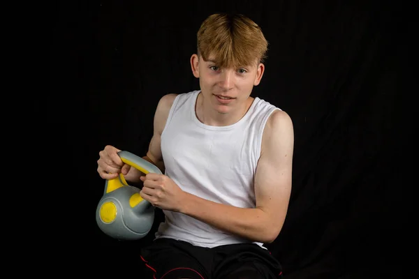 stock image Portrait of a 14 year old caucasian teenage boy wearing a sleeveless vest doing Russian twists against a black background boy