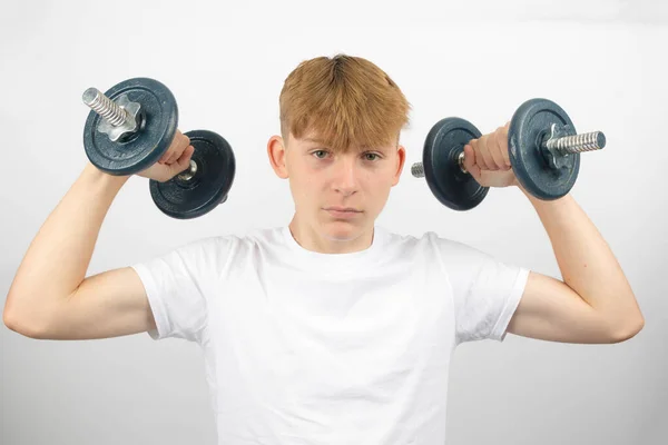 一个14岁的高加索少年用哑铃在双臂中的画像 — 图库照片