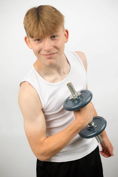 ダンベルを使用して袖のないベストを身に着けている14歳の白人十代の少年肖像画 — ストック写真