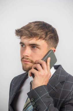 Takım elbiseli ve kravatlı genç bir girişimcinin cep telefonu kullanarak portresi