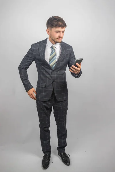 一个穿着西装打着领带的年轻企业家在电话上看信息的画像 — 图库照片