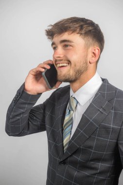 Takım elbiseli ve kravatlı mutlu bir girişimcinin portresi cep telefonu kullanıyor.