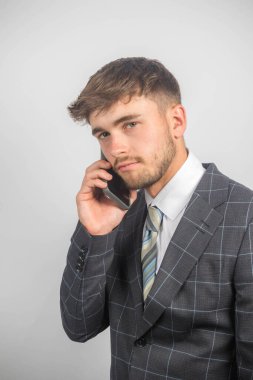 Takım elbiseli ve kravatlı genç bir girişimcinin cep telefonu kullanarak portresi