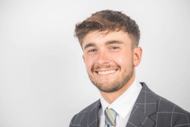 Takım elbiseli ve kravatlı genç bir girişimcinin gülümseyen portresi.