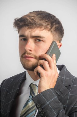 Takım elbiseli ve kravatlı genç bir girişimcinin cep telefonu kullanarak portresi