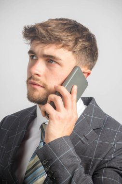 Takım elbiseli ve kravatlı genç bir girişimcinin cep telefonu kullanarak portresi