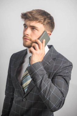 Takım elbiseli ve kravatlı genç bir girişimcinin cep telefonu kullanarak portresi