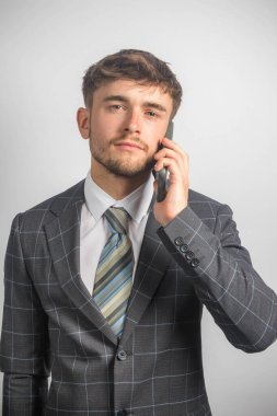 Takım elbiseli ve kravatlı genç bir girişimcinin cep telefonu kullanarak portresi