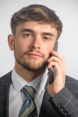 Takım elbiseli ve kravatlı genç bir girişimcinin cep telefonu kullanarak portresi