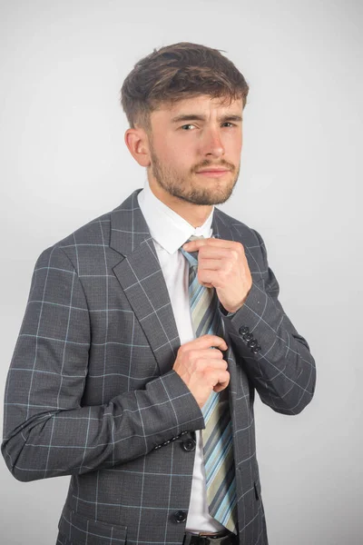 若い起業家の肖像画は 明白な背景に対して彼のネクタイを調整するスーツで — ストック写真