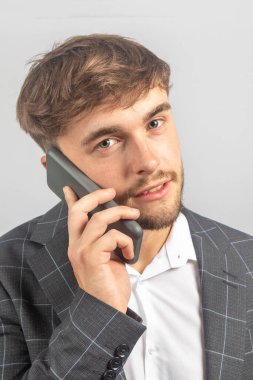 Genç bir işadamı ya da girişimcinin portresi, cep telefonuyla açık yaka gömlek giyiyor.