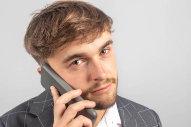 Genç bir işadamı ya da girişimcinin portresi, cep telefonuyla açık yaka gömlek giyiyor.