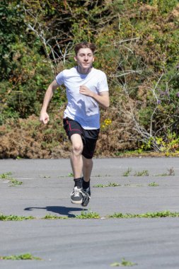 Sıcak bir öğleden sonra koşan formda ve sportif bir genç.