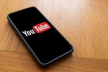 Londra, Birleşik Krallık, 5 Eylül 2023: - Bir Youtube logosunu gösteren ahşap bir masanın üzerinde bir cep telefonu