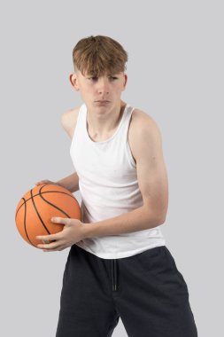 Beyazlı genç çocuk basketbol oynuyor.