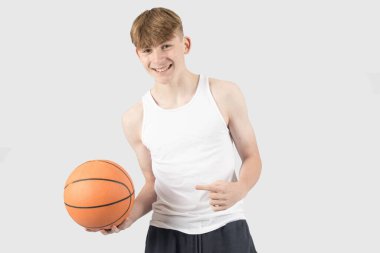 Kafkasyalı genç bir çocuk elinde bir basketbol topu tutuyor ve onu işaret ediyor.