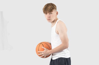 Beyazlı genç çocuk basketbol oynuyor.