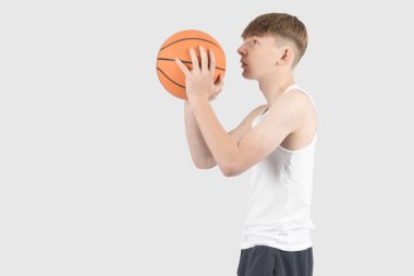 Elinde basketbol topu tutan beyaz bir çocuk.