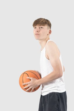 Beyazlı genç çocuk basketbol oynuyor.