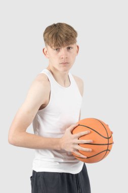 Beyazlı genç çocuk basketbol oynuyor.