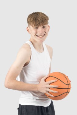 Elinde basketbol topu tutan ve gülümseyen beyaz çocuk.